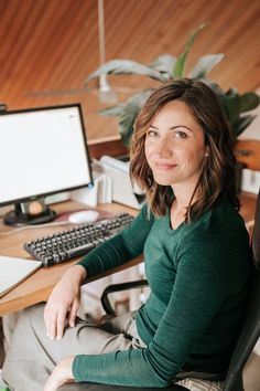 a woman sitting in front of a computer desk with a keyboard and monitor on it