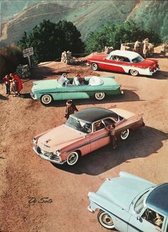 several old cars parked on the side of a dirt road