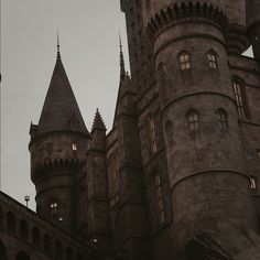 an old castle with two clocks on the front and one in the back, against a gray sky