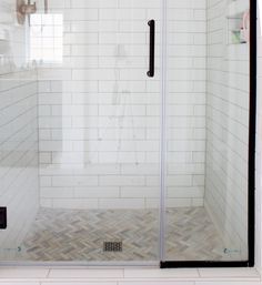 a walk in shower sitting next to a white tiled wall and floor with black trim