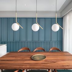 a wooden table with four lights hanging from it's sides in front of a blue wall