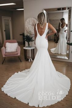 a woman standing in front of a mirror wearing a white dress