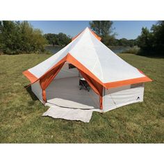 an orange and white tent sitting on top of a grass covered field