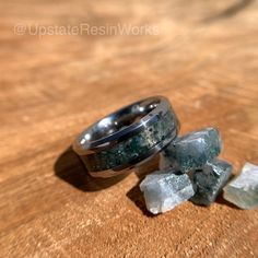 a couple of rings sitting on top of a wooden table next to some ice cubes