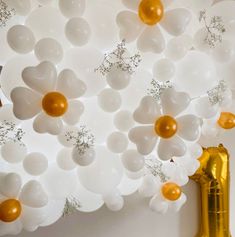 balloons and gold vases are hanging from the ceiling in front of a white wall