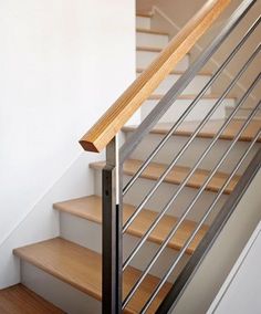 there is a wooden handrail next to the metal railing on this stair case that has been painted white