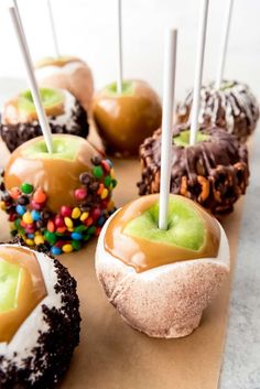 chocolate covered apples with caramel and sprinkles on a piece of brown paper