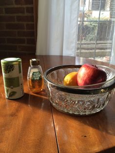 apples and honey sit on a table in front of a glass bowl with an apple