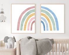 two framed rainbow prints in a baby's room with an elephant and crib