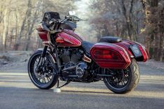 a red and black motorcycle parked on the side of a road in front of trees