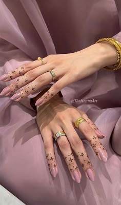 two woman's hands with tattoos and rings on their fingers, one wearing a pink dress