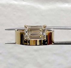 a diamond ring is being held by a pair of tongs