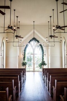 the inside of a church with pews and lights hanging from it's ceiling