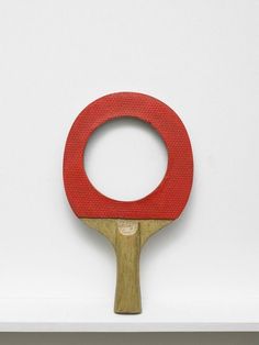 a red ping pong paddle on top of a white shelf