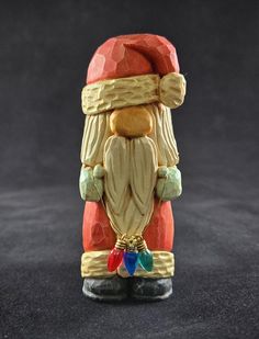 a small figurine is wearing a red santa hat and holding a blue bell