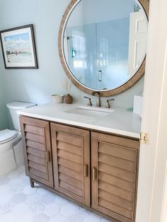 a bathroom with a large round mirror above the sink and wooden cabinet doors on the door