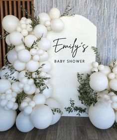 balloons and greenery decorate the backdrop for a baby shower