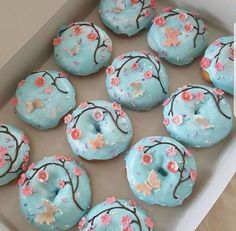 a box filled with blue frosted donuts covered in pink and white icing