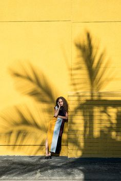 a woman standing in front of a yellow wall