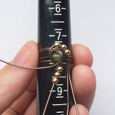 a person holding a piece of metal wire and measuring it with their fingers on the end