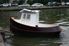 a black and white boat in the water next to a dock with cars on it