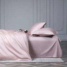 a bed covered in pink sheets and pillows