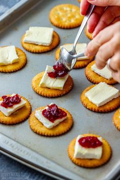 crackers with cheese and jam being spread on them