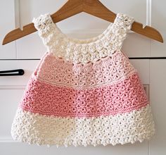 a crocheted dress hanging on a wooden hanger