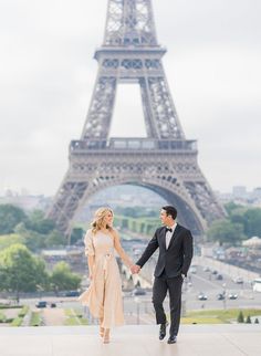 a man and woman holding hands in front of the eiffel tower