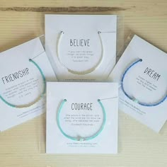 three bracelets with words on them sitting next to each other in front of some cards