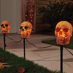 three lighted skull heads in the grass