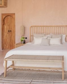 a bed with white linens and pillows in a room that has wooden beams on the ceiling