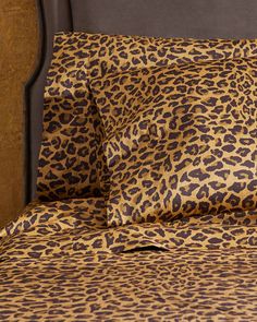 a bed with a leopard print comforter and matching pillow cases on top of it