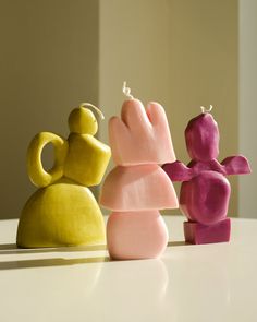 three small figurines sitting on top of a white table next to each other