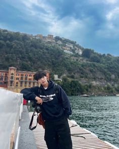 a man is standing on a dock by the water