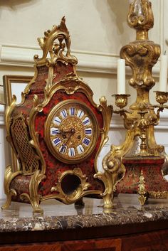 an ornate clock sitting on top of a table next to two candelabras