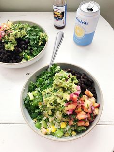 two bowls filled with salad next to a can of soda on top of a table