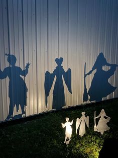 three silhouettes of people and children in front of a metal wall with shadows on it