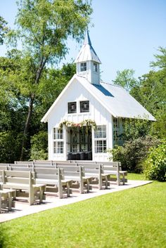 a small white church with benches in front of it