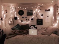 a bedroom with lights strung from the ceiling and a laptop computer on top of it