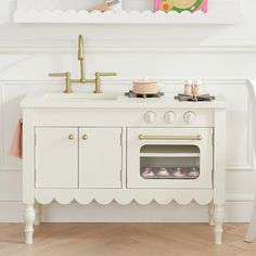 a white kitchen with an oven, sink and painting on the wall above it's stove