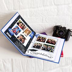 an open photo book with pictures and a camera on the cover is sitting on a white surface