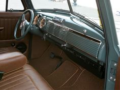 the interior of an old car with brown leather seats and tan dash cloth on the floor