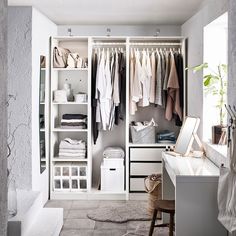 an open closet with clothes hanging on the shelves and drawers, along with a sink