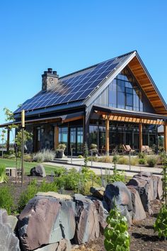 a house with large rocks in front of it and a solar panel on the roof