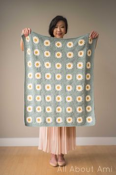 a woman is holding up a granny granny's sunflower crochet blanket