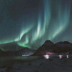 the northern lights shine brightly over mountains and water