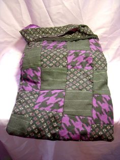 a green and purple quilted bag sitting on top of a bed