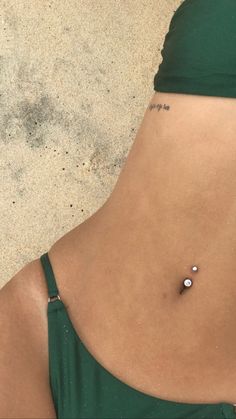 a woman's stomach with a tiny tattoo on her left side and two balls in the middle