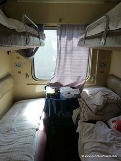 two beds in a small room with curtains on the window sill and one bed is empty